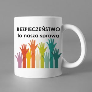 Na obrazku przedstawiony jest biały ceramiczny kubek z nadrukiem rąk i napisem " Bezpieczeństwo to nasza sprawa" - Kubki BHP Proresult