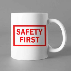 Na obrazku przedstawiony jest biały ceramiczny kubek z czarnym nadrukiem SAFETY FIRST - Kubki BHP Proresult