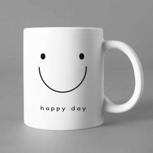 Na obrazku przedstawiony jest biały ceramiczny kubek z nadrukowanym uśmiechem i napisem happy day - Wellbeing BHP Proresult